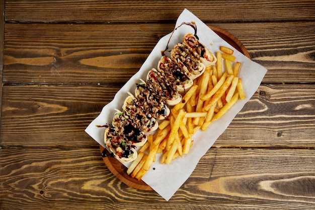 Sliced meat roll in pita bread and french fries top view