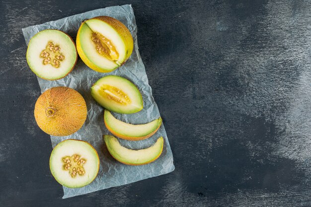 Sliced melon on a dark wooden and gray cloth background. top view. space for text