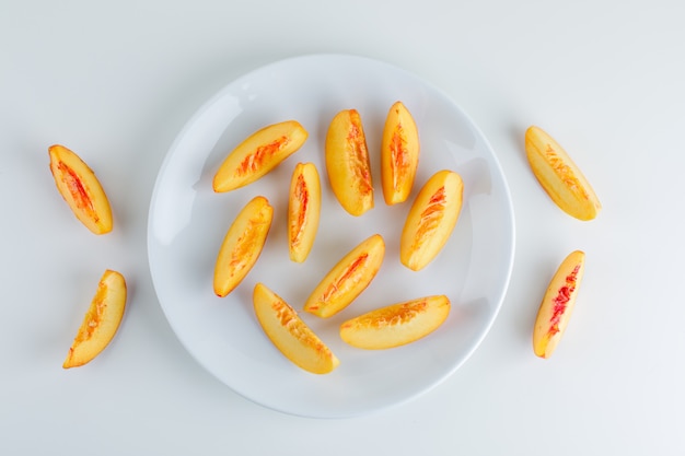 Free photo sliced nectarine in a plate on a white surface. flat lay.