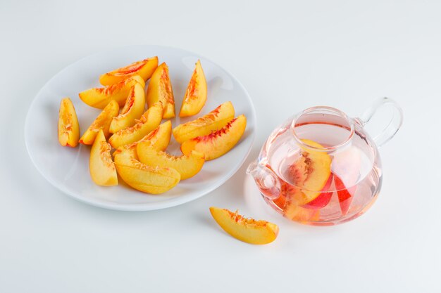 Sliced nectarine in a plate with drink high angle view on a white surface