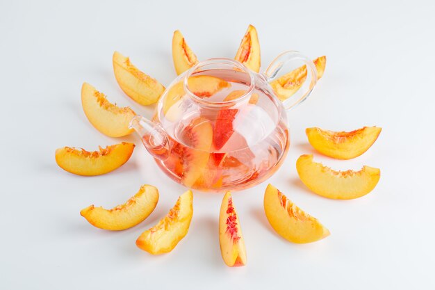 Sliced nectarine with summer drink high angle view on a white surface