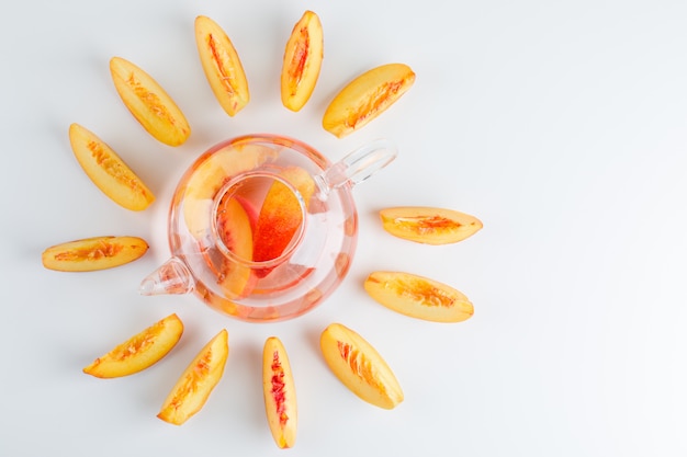 Sliced nectarine with summer drink top view on a white surface