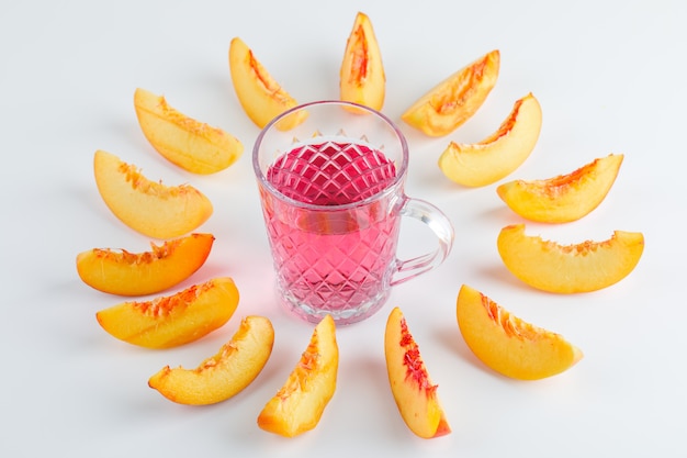 Sliced nectarine with summer drink on white table, high angle view