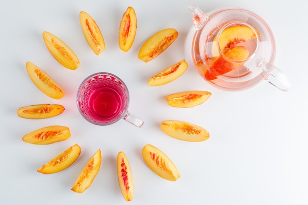 Sliced nectarine with summer drink on white table, top view.