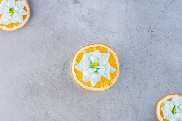 Free photo sliced orange fruit with white flowers on gray