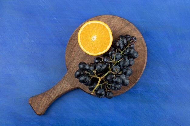 Sliced orange with grapes on wooden board 