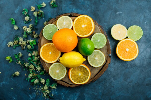 Sliced orange with lime, lemon, dried flowers flat lay on grungy blue and wooden board 
