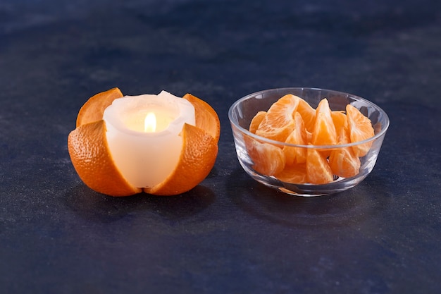 Нарезанные апельсины и расплавленная свеча на серой поверхности