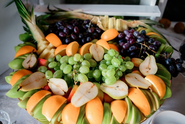 Sliced oranges, pears, apples and grape served on large dish 