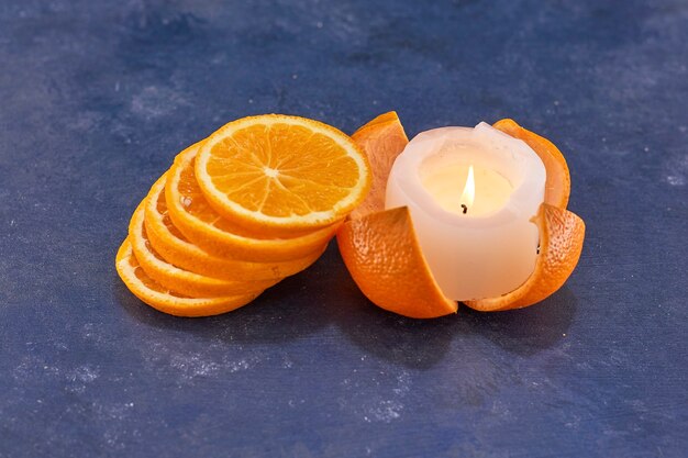 Кучу нарезанных апельсинов на синем с горящей свечой в стороне