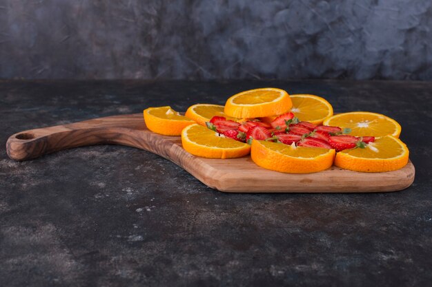 Нарезанные апельсины и клубника на деревянной доске