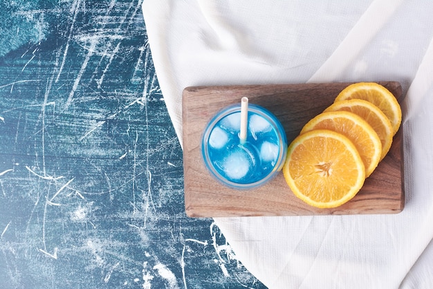 Sliced oranges with a glass of juice on blue.