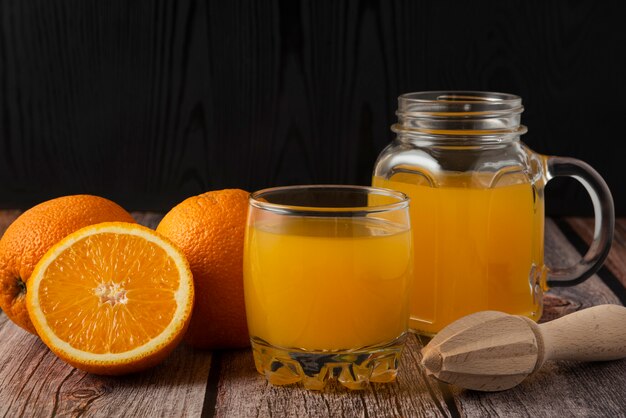 Sliced oranges with juice in the glass jar and cup
