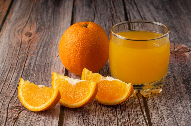 Sliced oranges with juice in the glass jar and cup