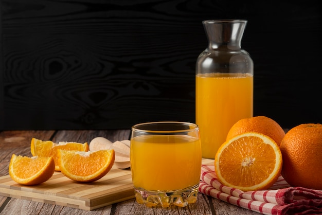 Free photo sliced oranges with juice in the glass jar and cup