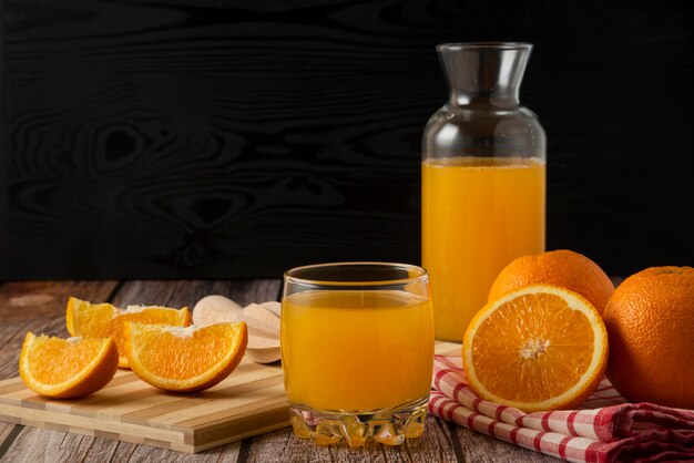 Sliced oranges with juice in the glass jar and cup