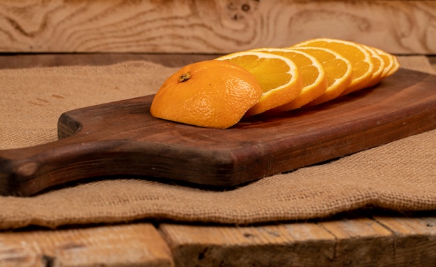 Arance affettate su una tavola di legno su una tela da imballaggio. vista laterale.