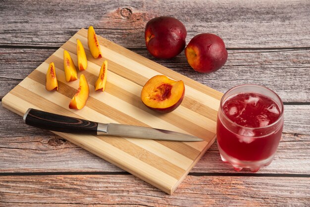 Sliced peach on a wooden cutting board with a cup of ice drink