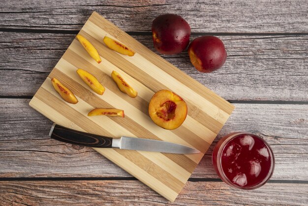 Sliced peach on a wooden cutting board with a cup of ice drink