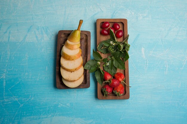 Sliced pears with strawberries and mulberries in wooden platters in the center