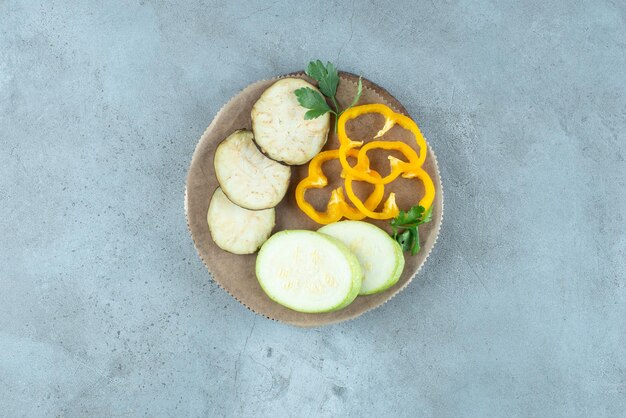 Sliced pepper, eggplant and zucchini on ceramic plate.