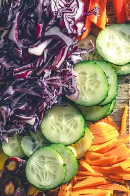 Free photo sliced peppers cucumber and blue cabbage on a cutting board closeup