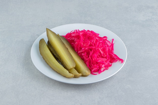 Sliced pickles cucumber next to sauerkraut on a plate   