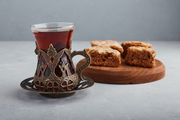 Sliced pie on a wooden platter with a glass of tea. 