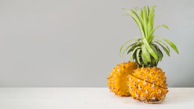 Sliced pineapple fruit in front of grey wall