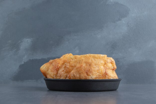 Sliced piroshki with potatoes in black bowl.