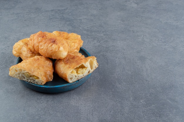 Sliced piroshki with potatoes on blue plate.