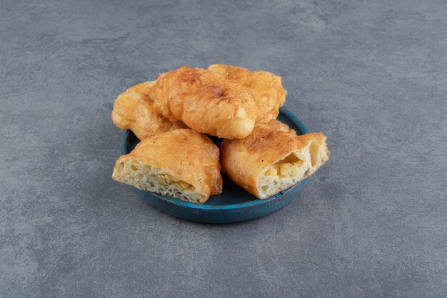 Sliced piroshki with potatoes on blue plate.