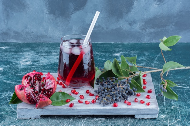 A sliced of pomegranate and juice on the board , on the blue table.