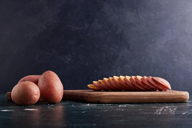 Sliced potato on wooden board.