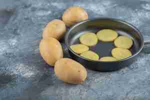 Free photo sliced potatoes inside of pan on grey background. high quality photo