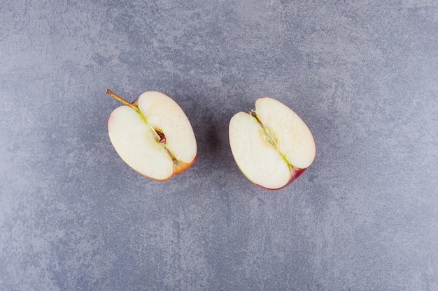 Free photo sliced red apple fruit placed on a stone table .