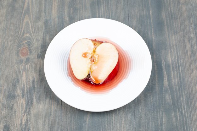 흰색 접시에 주스에 빨간 사과 슬라이스