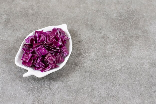 Sliced red cabbage in a bowl, on the marble table. 