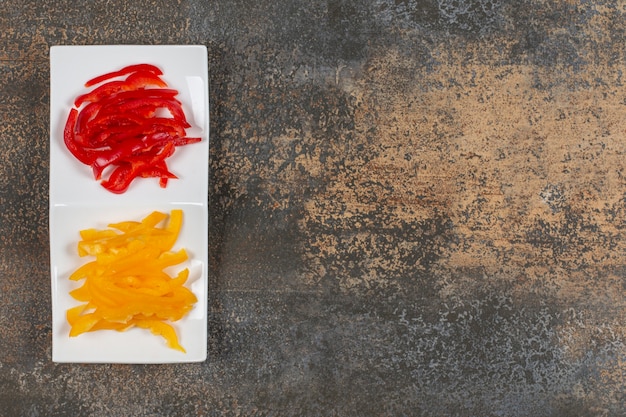 Free photo sliced red and yellow peppers on white plate.