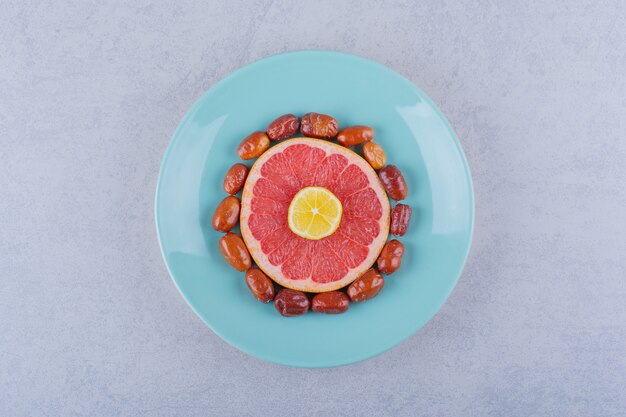 Sliced ripe grapefruit, lemon and silverberries on blue plate.