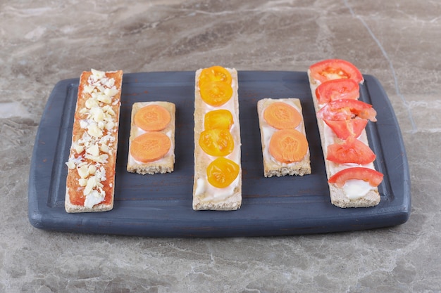 Sliced ripe and unripe tomatoes on crispy breads on the cutting board, on the marble surface