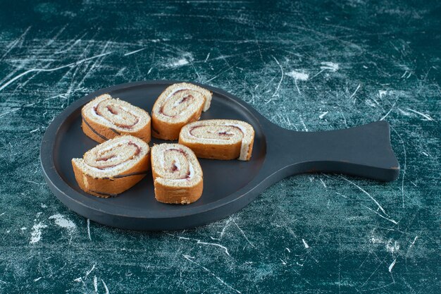 Sliced roll cakes on a pan, on the blue background. High quality photo