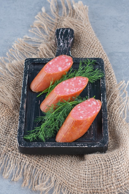 Salame affettato di salsiccia su tavola di legno con spezie.