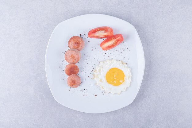 Sliced sausages and egg on white plate. 