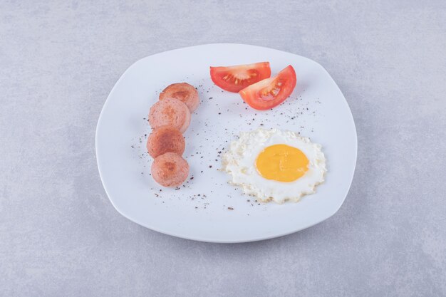 Sliced sausages and egg on white plate. 