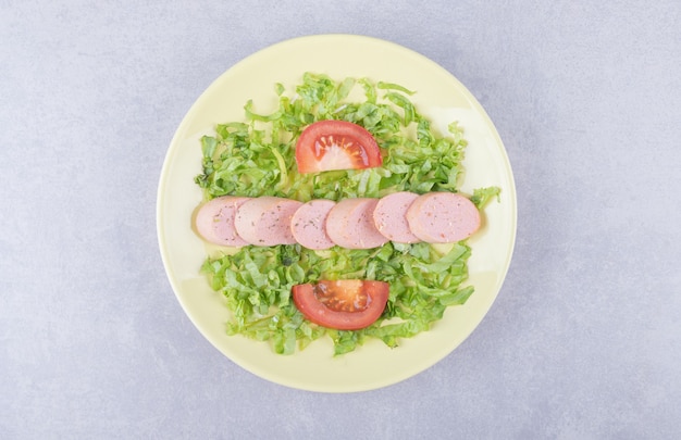 Sliced sausages and tomatoes on yellow plate. 