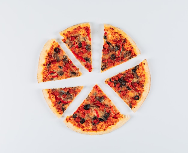 Sliced savoury pizza on a light blue stucco background. flat lay.