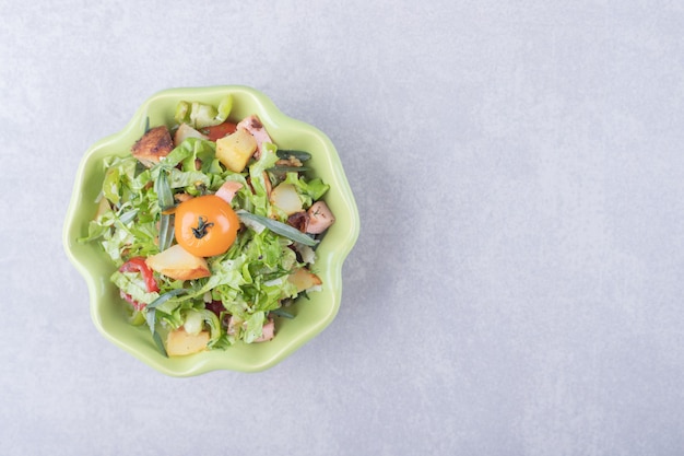 Free photo sliced smoked sausages, lettuce and tomato in green bowl.