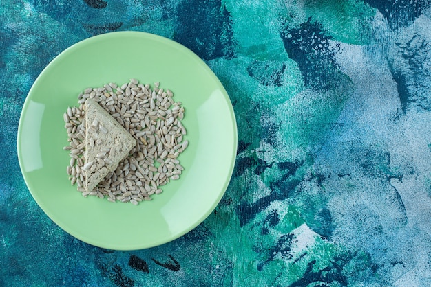 Halva di girasole affettato con semi sul piatto, sul tavolo di marmo.