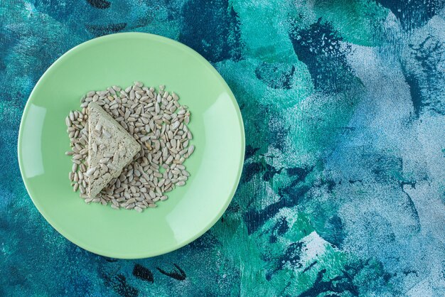 Sliced sunflower halva with seeds on plate on marble. 